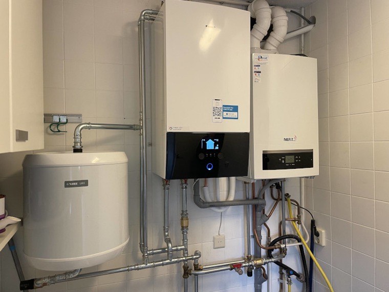 Hybride opstelling: warmtepomp-binnenunit naast een cv-ketel en boiler, met verzorgd leidingwerk